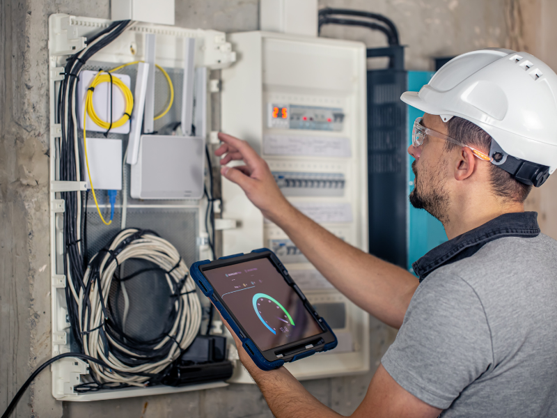 Électricien installant un tableau électrique moderne avec disjoncteurs dans un intérieur résidentiel