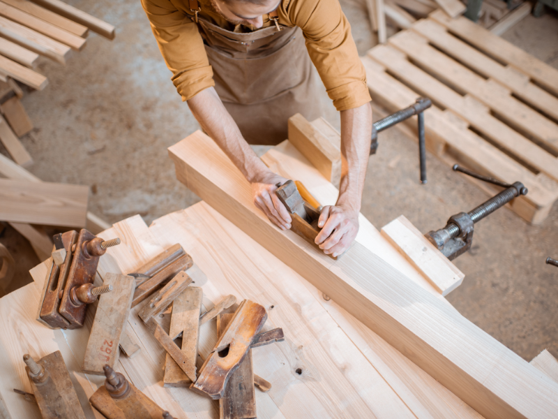 Menuisier artisan travaillant sur une porte en bois massif dans son atelier avec outils traditionnels